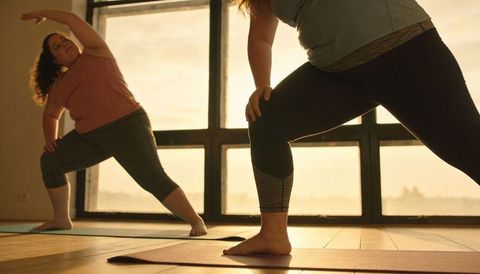 Sunlit studio yoga with plus-size women practicing lunge and side stretch