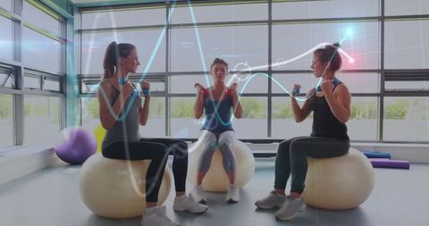 Women exercising with dumbbells on balls in bright fitness studio