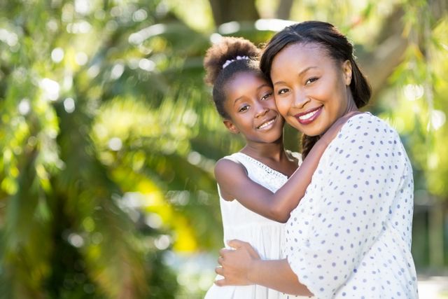 Mother and daughter enjoying time together in a lush green park. Perfect for themes related to family bonding, parenting, outdoor activities, and joyful moments. Suitable for use in advertisements, family-oriented content, and lifestyle blogs.