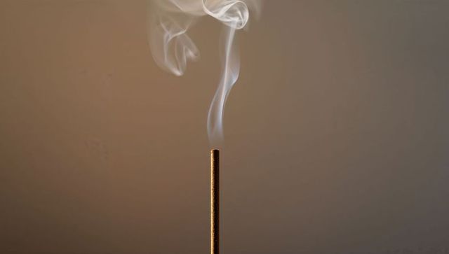 Smoldering Incense Stick with Delicate Smoke Trail on Neutral Background for Calm Rituals