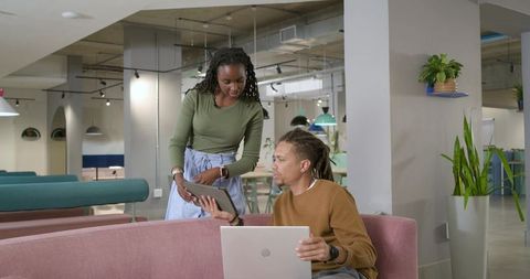 African american coworkers collaborating in modern coworking lounge showing tablet