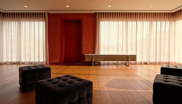 Tufted charcoal ottoman in minimalist modern lounge with sheer curtains and warm oak floor
