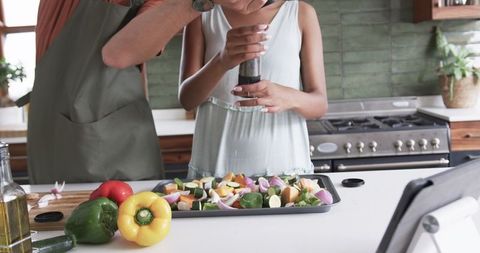 Couple Seasoning Fresh Vegetables in Modern Kitchen