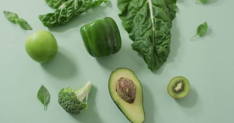 Fresh green vegetables and fruits on styled background