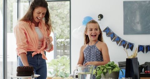 Mother and Daughter Preparing Birthday Celebration with Joyful Laughter
