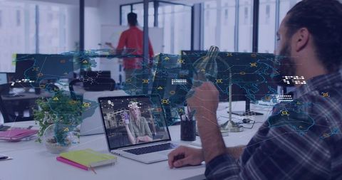 Bearded man holding coffee watching remote video call with AR map overlay in open office
