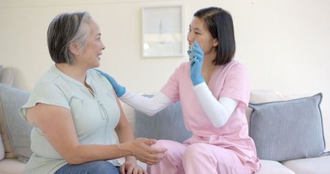 Nurse Assisting Senior Asian Woman in Home Physical Therapy Session