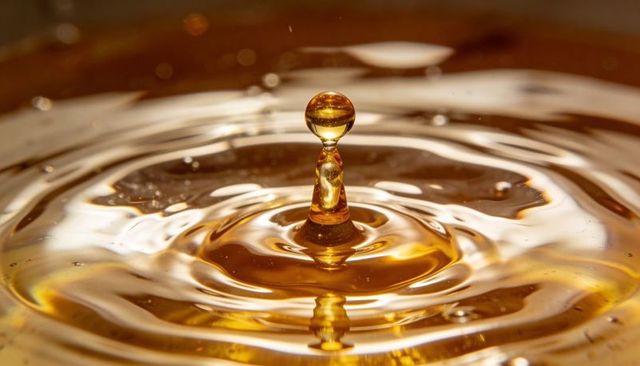 Rebounding golden droplet forming tapered column with concentric ripples