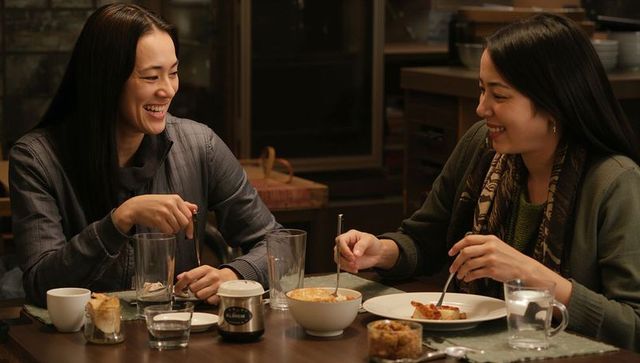 Smiling friends sharing cozy homemade dinner at rustic wooden table, intimate evening