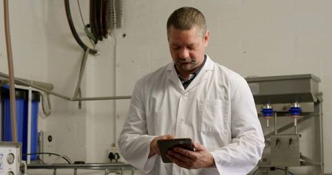 Technician Utilizing Tablet for Equipment Monitoring in Industrial Facility