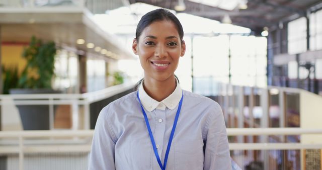 Professional Woman Smiling in Office Environment with ID Badge - Download Free Stock Images Pikwizard.com