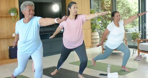 African american women practicing yoga at home together in living room wellness session
