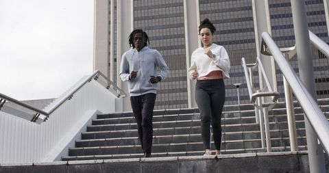 African American man and woman jogging down urban stairs for outdoor fitness training