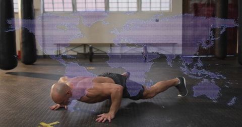 Athletic man performing wide-arm push-up in gym