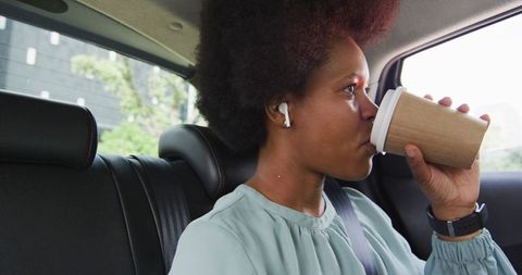 Businesswoman commutes in car while drinking coffee