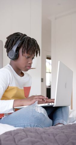 African American Boy Enjoying Laptop with Headphones on Bed - Download Free Stock Images Pikwizard.com