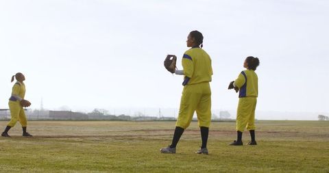 Female softball players in yellow uniforms on baseball field