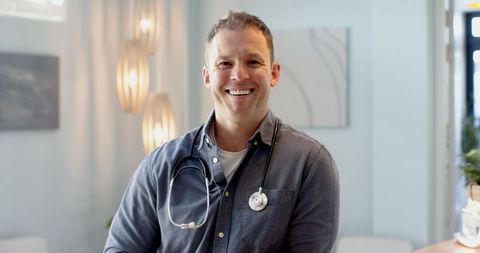 Doctor smiling confidently in modern consultation room with stethoscope