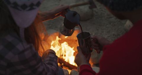 Couple Enjoying Coffee by Campfire in Mountain Setting