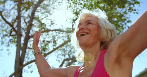 Joyful Senior Woman Practicing Yoga Outdoors in Sunlit Garden