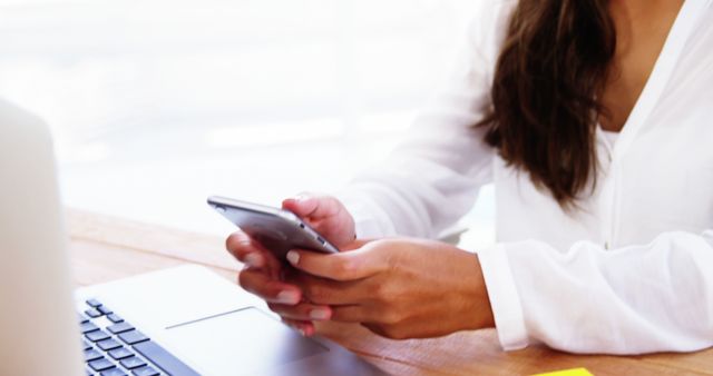 Woman Using Smartphone at Office Desk with Laptop - Download Free Stock Photos Pikwizard.com