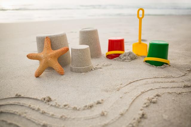 Bucket, spade, starfish and sand castles on tropical sand beach