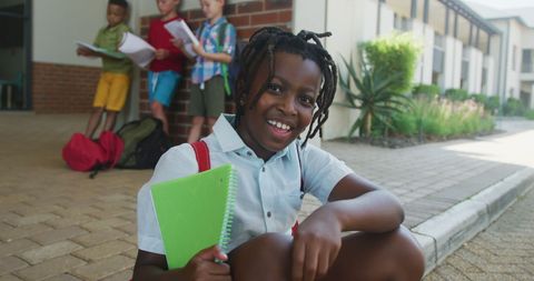 Joyful African American Boy Holding Notebooks at School