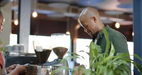 African american barista preparing espresso at busy coffee counter with customer