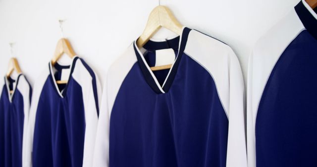 Row of Blue and White Sports Jerseys Hanging on Wooden Hangers - Download Free Stock Images Pikwizard.com