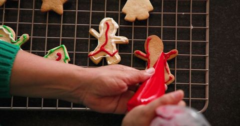 Woman Decorating Festive Gingerbread Cookies with Red Icing
