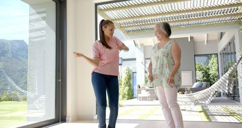 Grandmother and Granddaughter Dancing Joyfully on Sunlit Patio