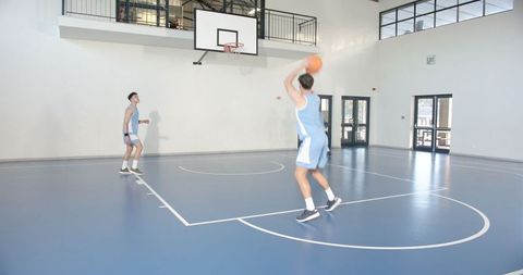 Male teammates practicing free-throws on indoor court