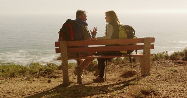 Couple With Backpacks Sitting On Bench Near Ocean During Daytime - Download Free Stock Images Pikwizard.com