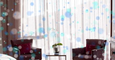Sunlit hotel sitting area featuring pair of armchairs, orchid on glass table, soft bokeh