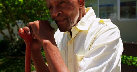 Contemplative Senior Man with Walking Stick in Garden