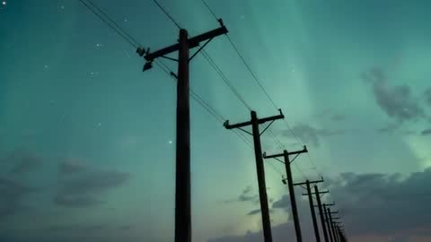 Panning Camera Tracing Wooden Utility Poles and Power Lines Under Aurora Night Sky