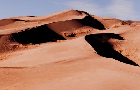 Sunlit desert dunes casting deep shadows across wind-sculpted sand ridges