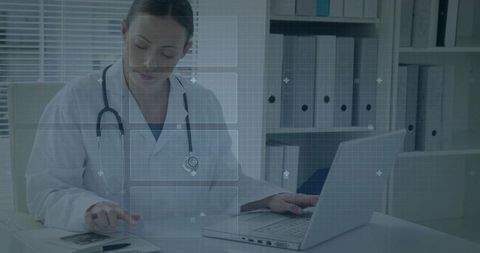 Female doctor reviewing x-ray on laptop updating digital medical records in clinic