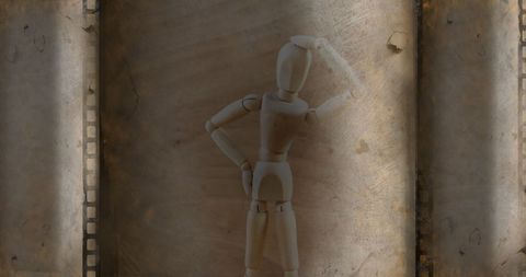 Wooden mannequin posing against film reel background