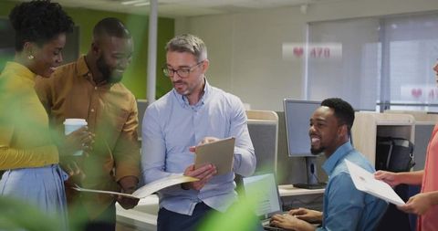 Business Team Collaborating in Open-Plan Office Manager Showing Tablet During Brainstorm Session