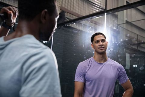 Training partners discussing technique in industrial gym near mirror with rimlight flare