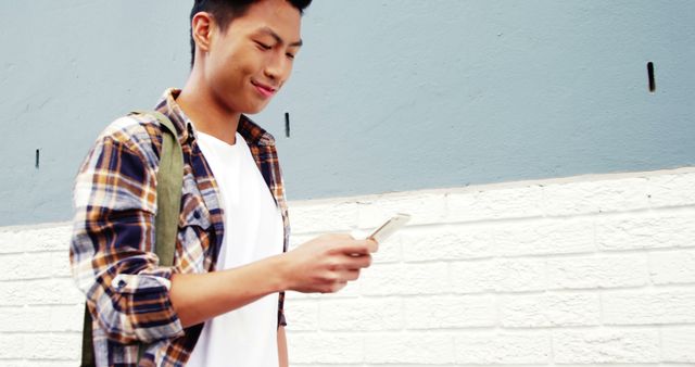 Young man texting on smartphone while walking on city sidewalk - Download Free Stock Images Pikwizard.com