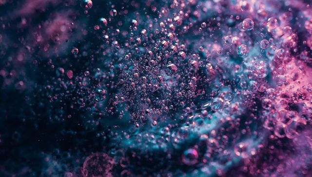 Shimmering microbubble macro with teal magenta iridescent bokeh and liquid refraction