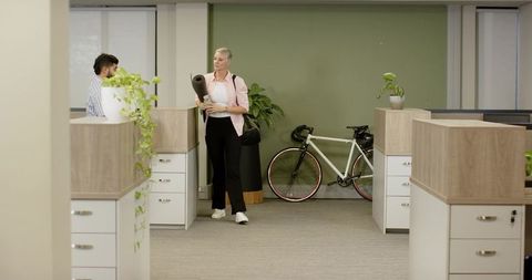 Diverse coworkers with yoga mat next to bicycle in modern office