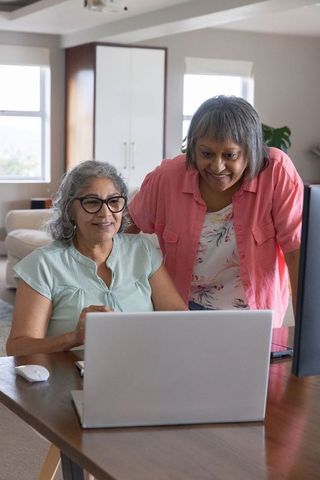 Senior women collaborating in cozy home workspace using laptop