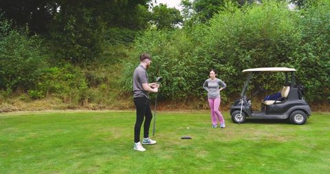 Golf Instructor Coaching Student on Grass Course