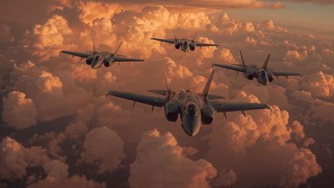 Fighter jets in diamond formation at airstrikes sunset above clouds