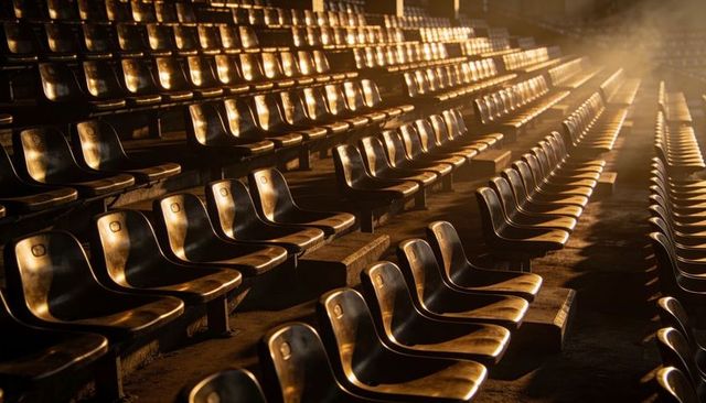 Golden hour lighting on empty stadium seats, repeating rows and diagonal perspective