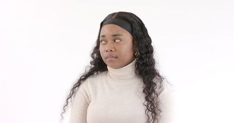 African american woman in beige sweater looking thoughtful