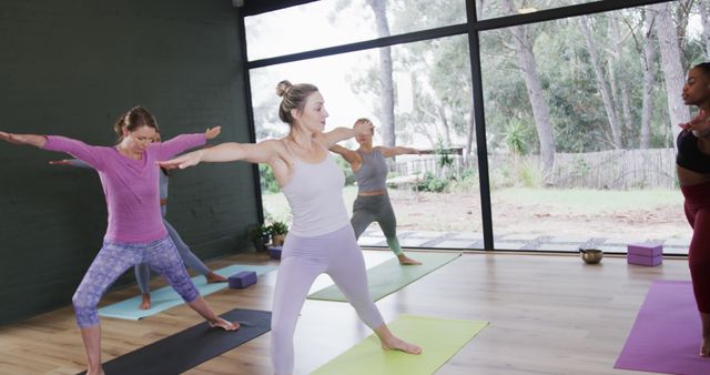 Diverse individuals performing yoga poses with an instructor leading the session. The bright and airy studio makes it a perfect setting for promoting health, wellness, and mindfulness. Ideal for promoting fitness classes, wellness blogs, and meditation retreats.